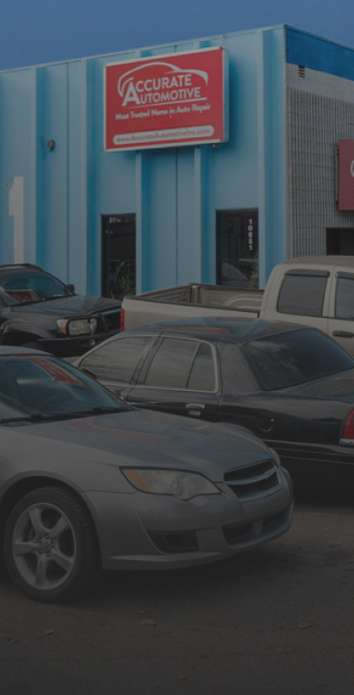 Parking lot outside a blue commercial building with a red sign and several parked cars in front | Accurate Automotive Northglenn