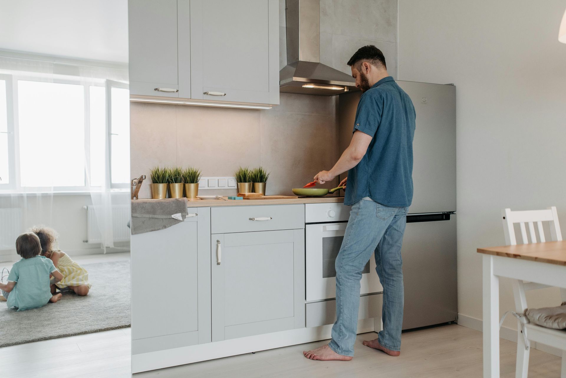 Person chopping vegetables in a bright kitchen while a child plays on the floor nearby