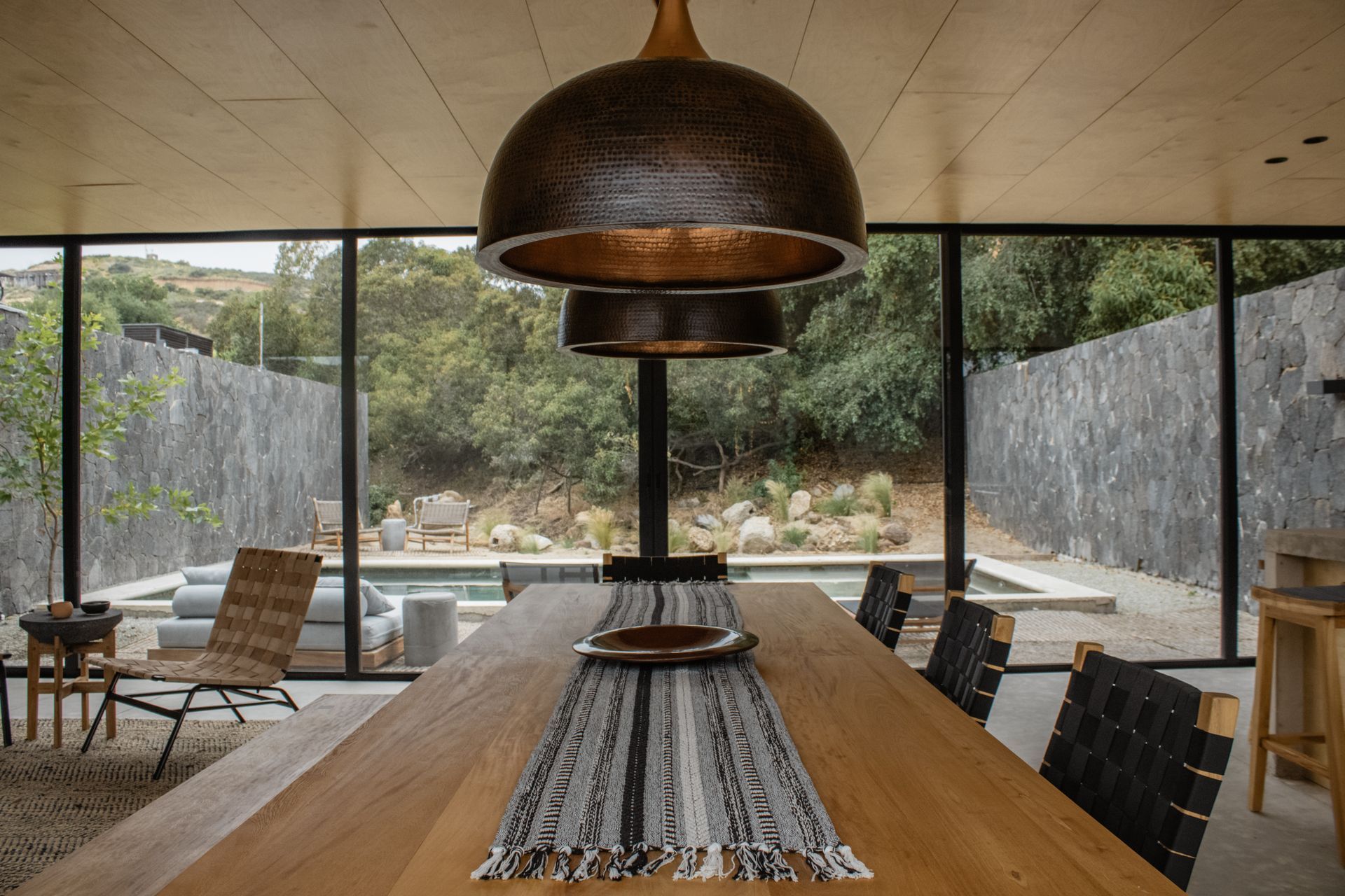 Bedroom with balcony overlooking a lush green landscape; two chairs, rug, and small table.