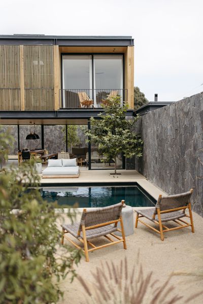 Bedroom with balcony overlooking a lush green landscape; two chairs, rug, and small table.