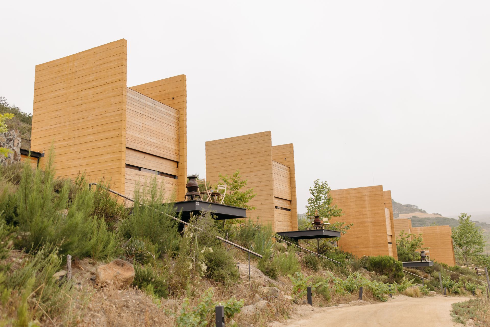 Tent on wooden platform with chairs and table, under trees.