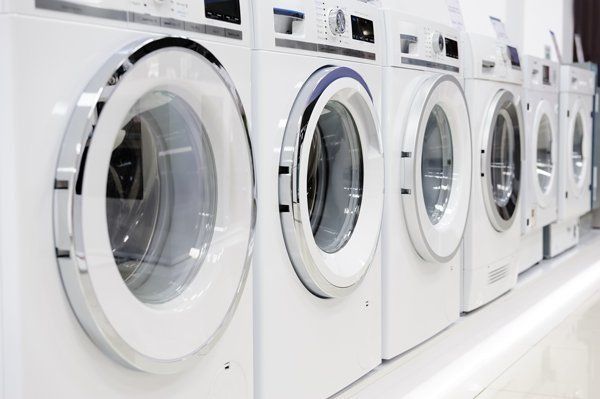A row of white Washing Machines are Lined up in a Laundromat — The Latest Home Appliances in Rockhampton