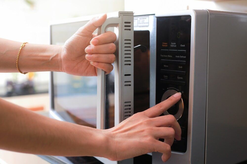 A Person is Opening a Microwave oven with their Finger — The Latest Home Appliances in Rockhampton