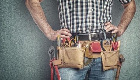 Burnaby Handyman wearing a plad button up shirt with his hand on his hips wearing a construction tool belt.