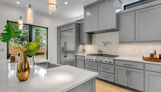 Picture of a fully renovated kitchen by Burnaby Handyman using handyman services. The kitchen cabinets are grey and the island has a white counter top and open concept.