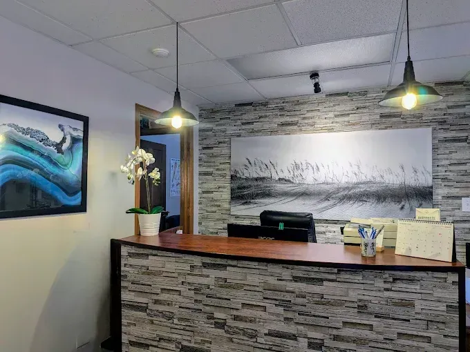 Reception area with stone-textured counter, art, pendant lights, and an open doorway.