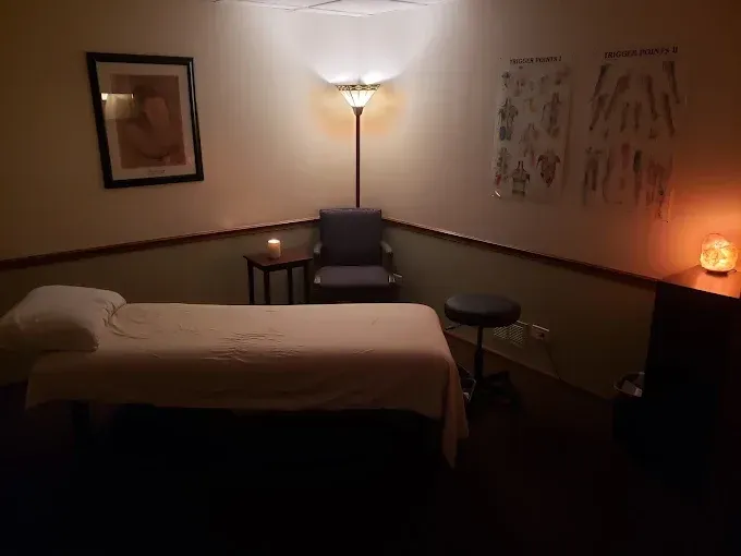 Massage room with massage table, chair, and dimmed lighting.
