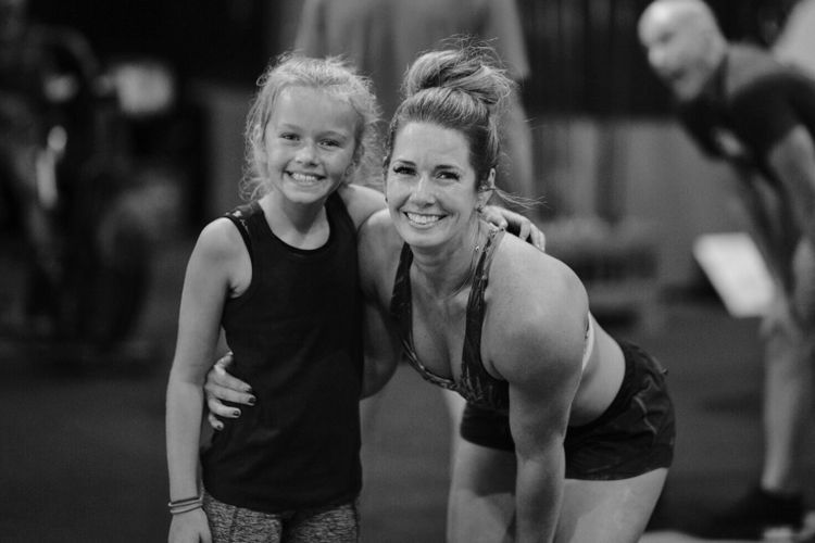A woman and a little girl are posing for a picture in a gym.