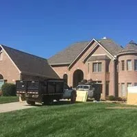 A dump truck is parked in front of a large brick house.