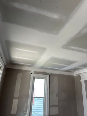 Room interior with newly installed drywall on ceiling and walls. Window visible.
