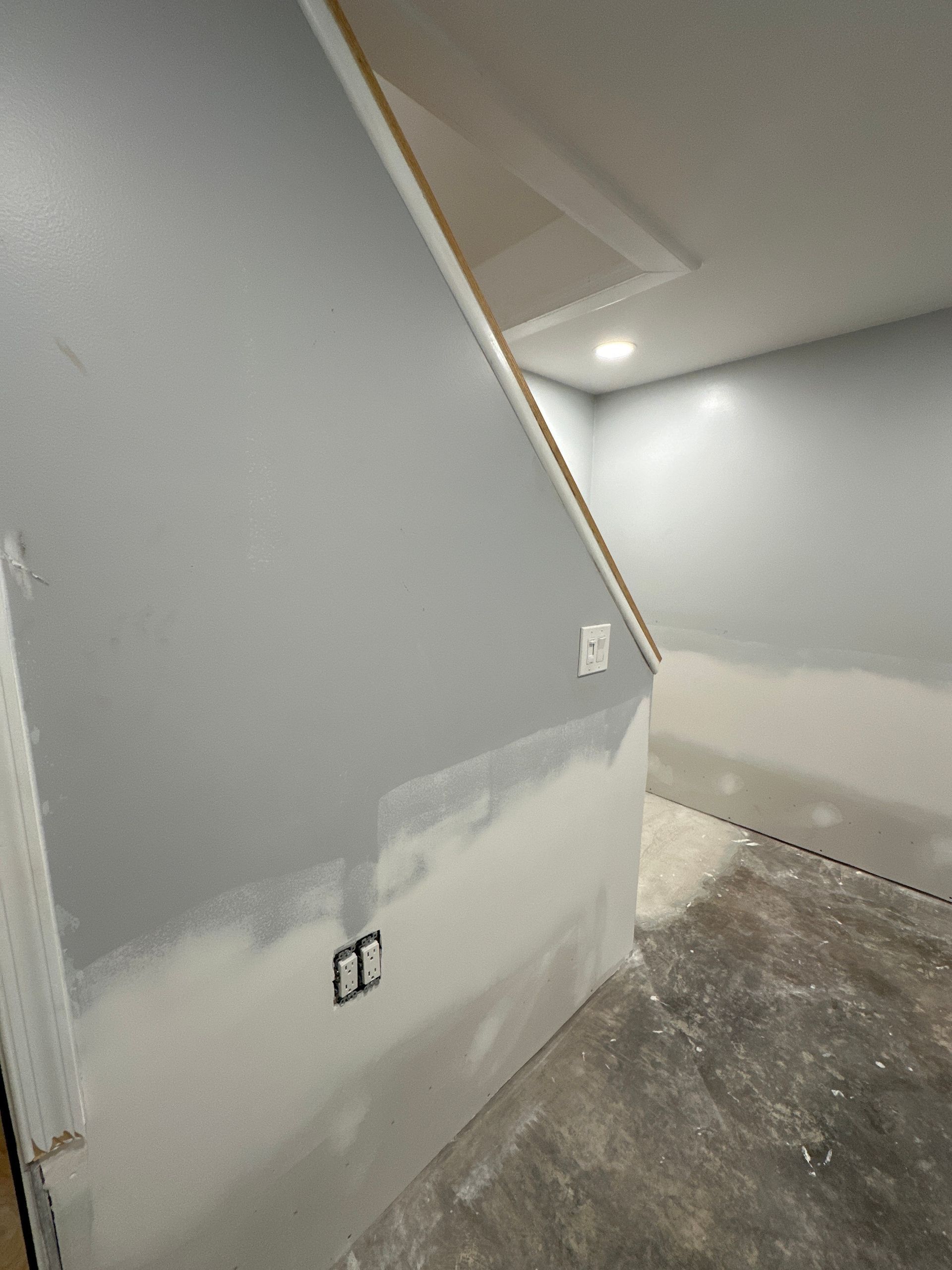 Gray and white painted walls of a room under construction, with electrical outlets and a doorway.