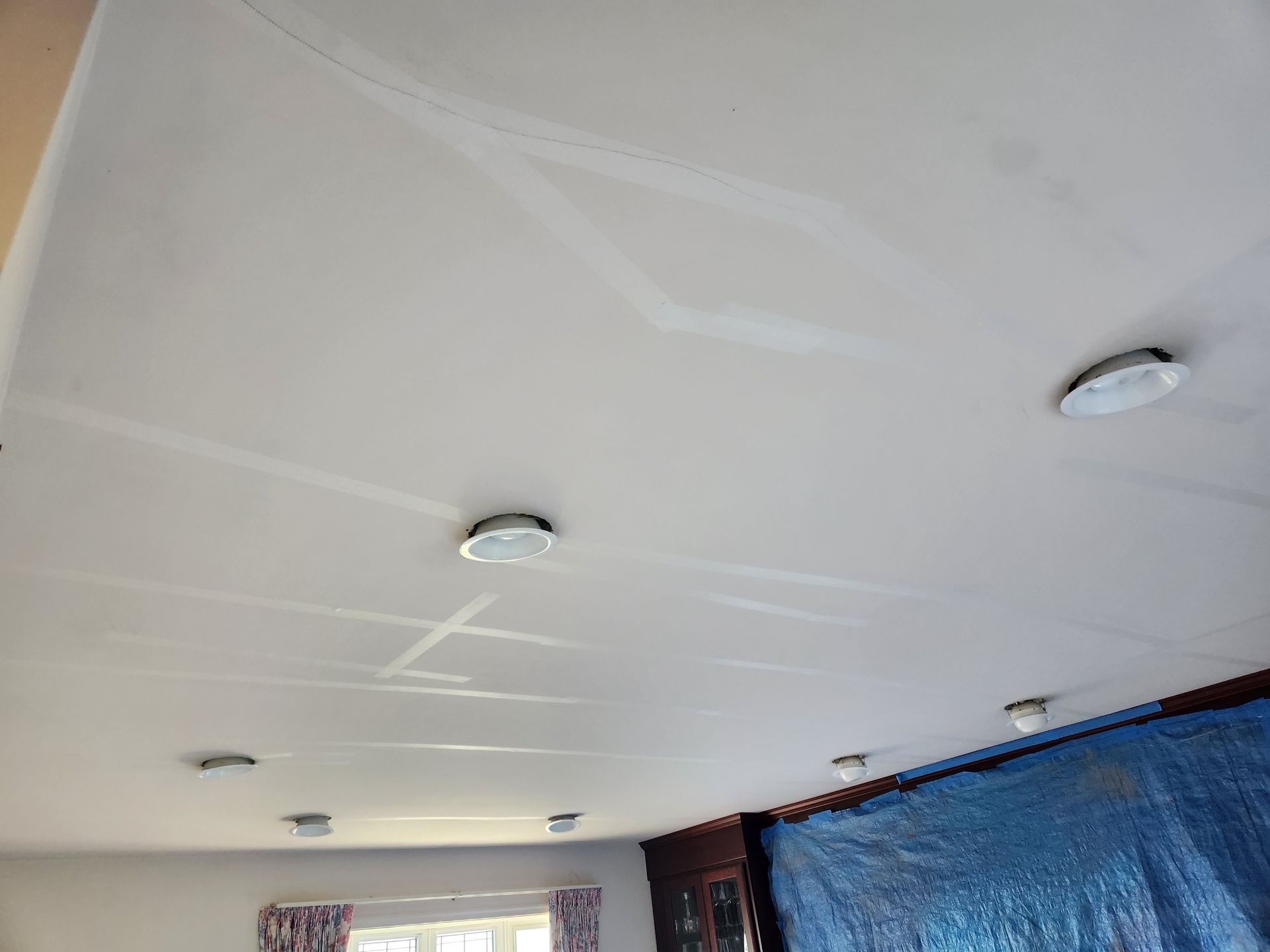 White ceiling with six recessed lights and patched drywall.