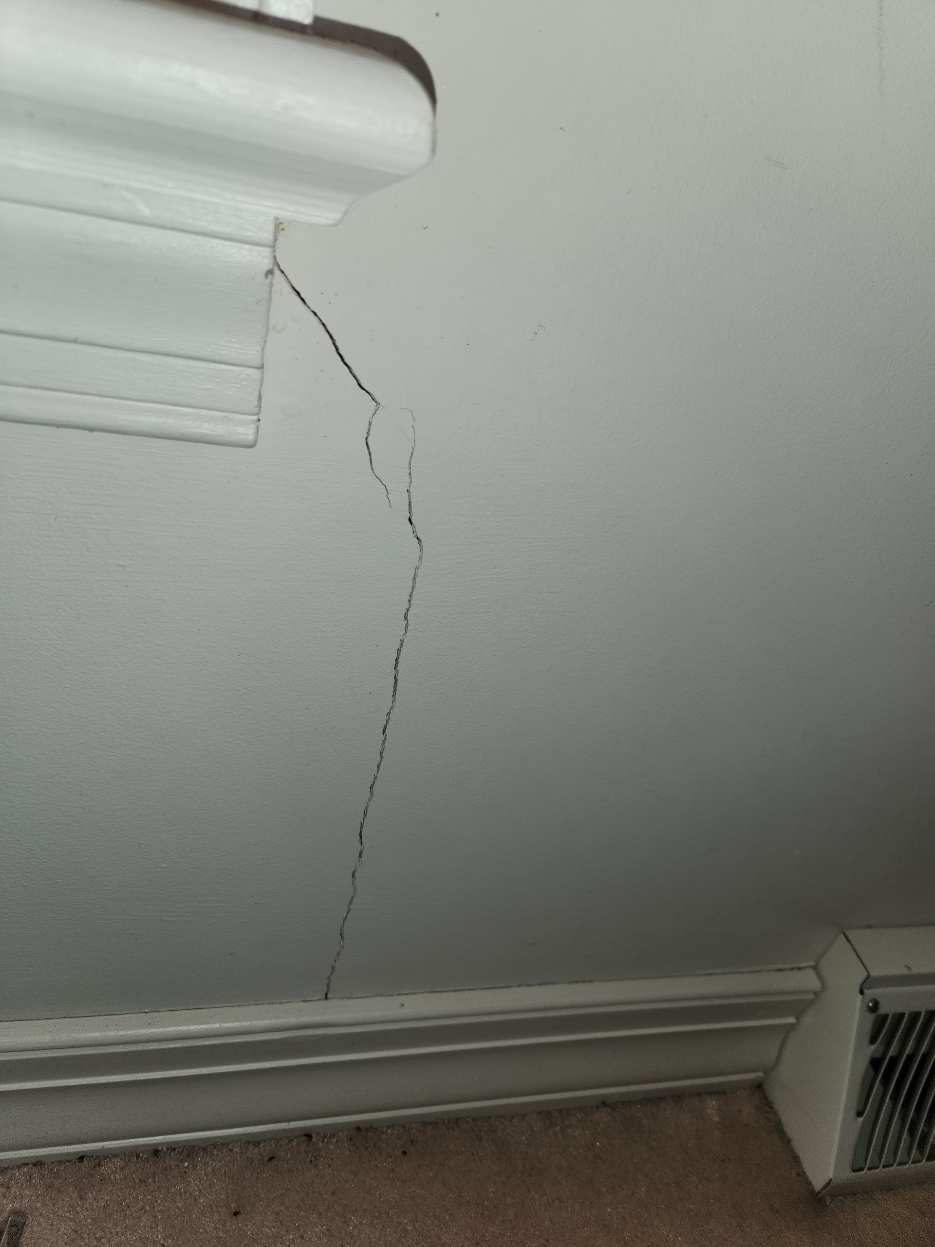 White wall with long vertical crack, near white molding.