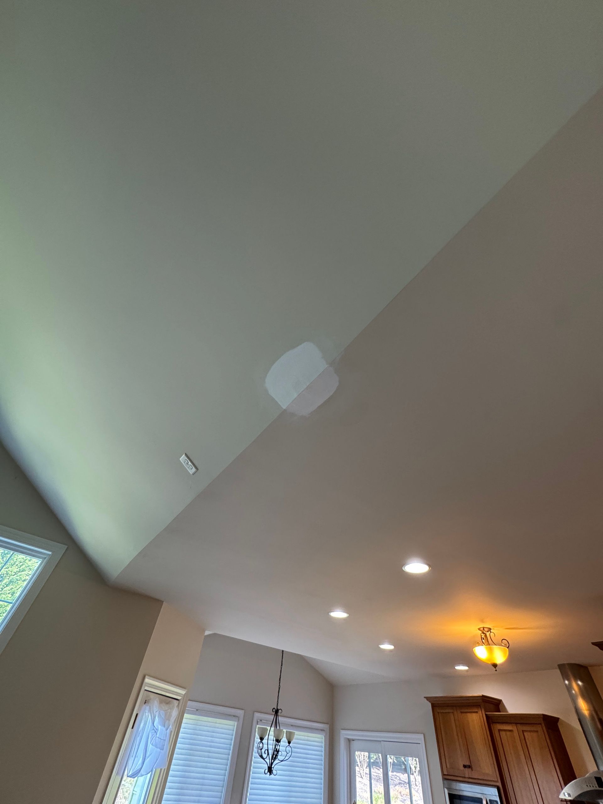 White ceiling with a patched area. Recessed lighting and windows are visible.