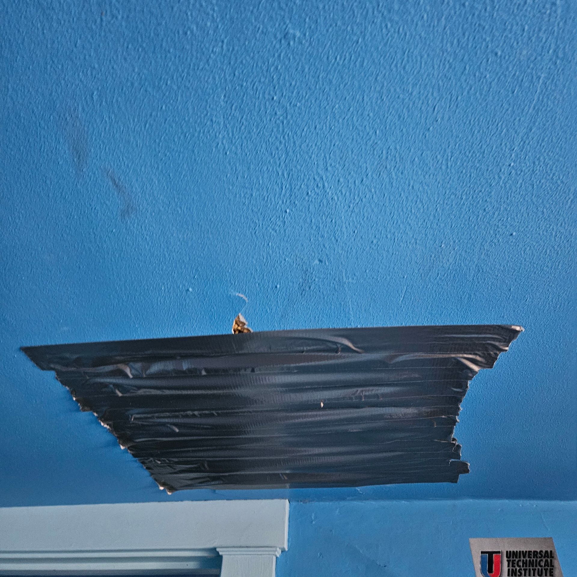 Blue ceiling with a large patch of black tape covering a damaged area.
