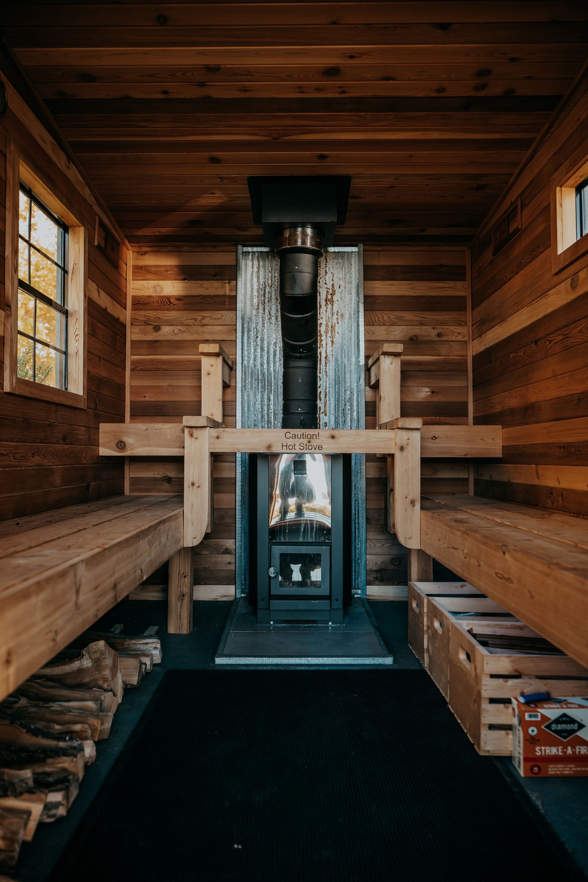 A wooden sauna with a wood stove and benches.