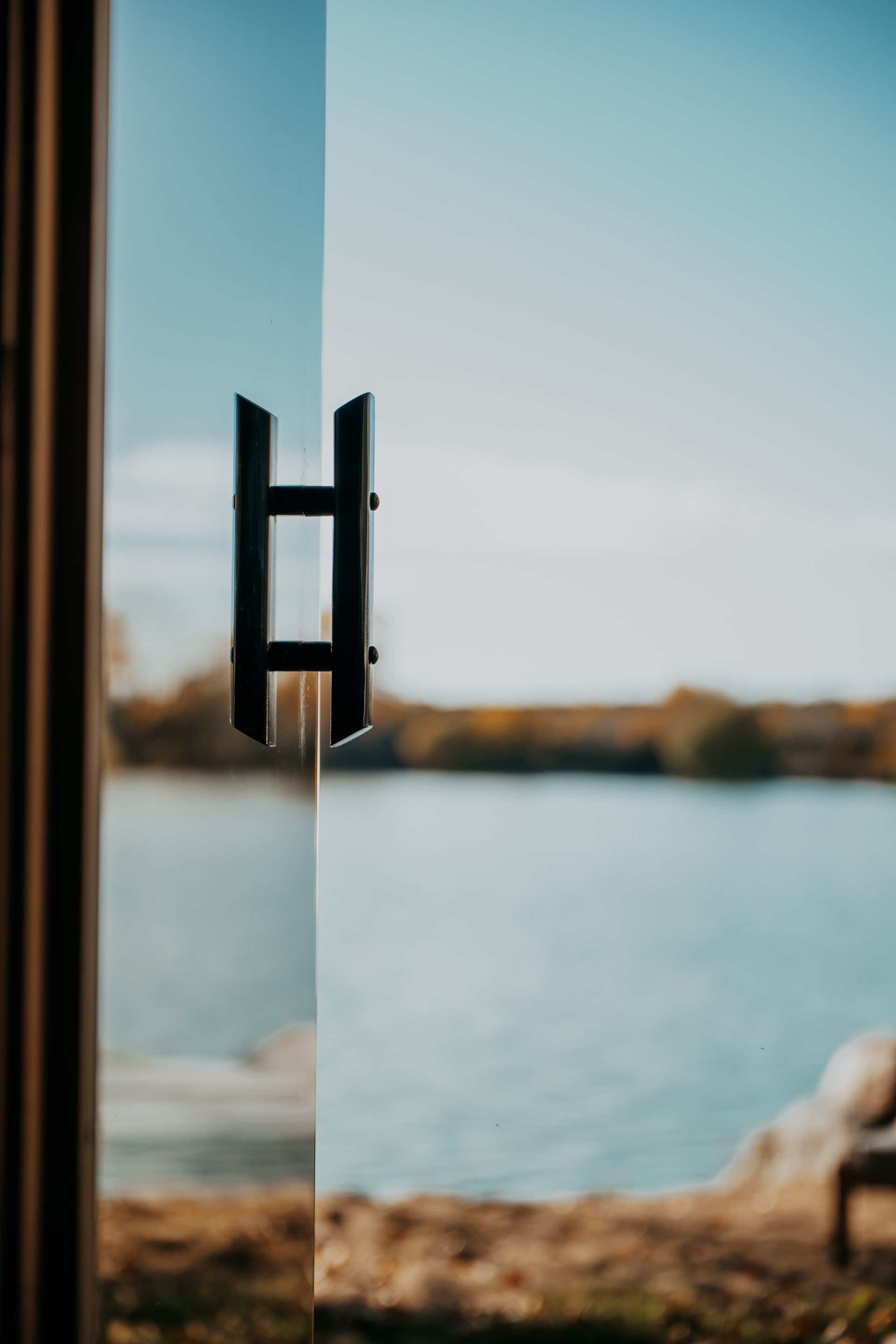 A door with a handle and a view of a lake.