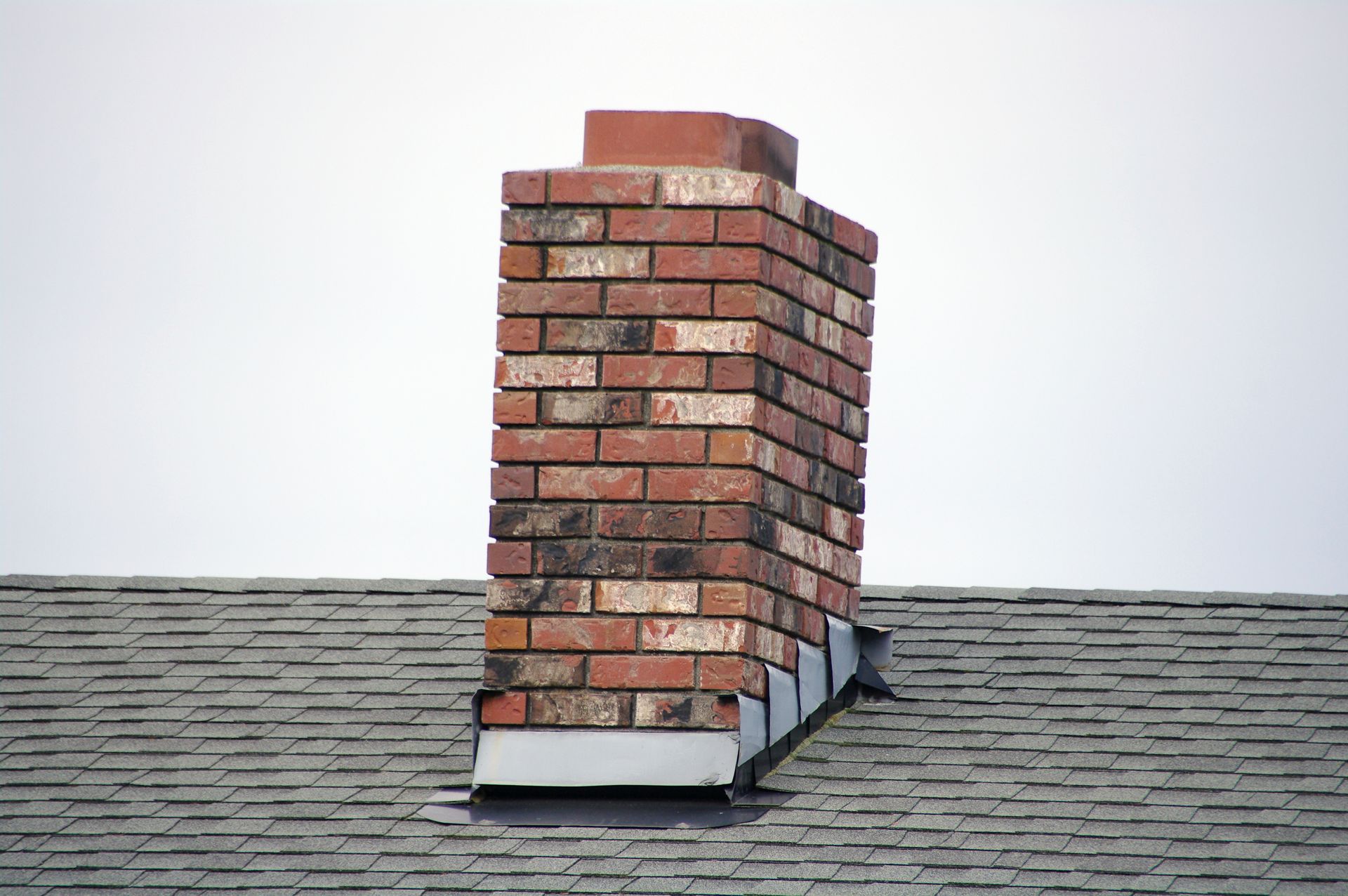 A roof with a chimney on it and a cloudy sky in the background