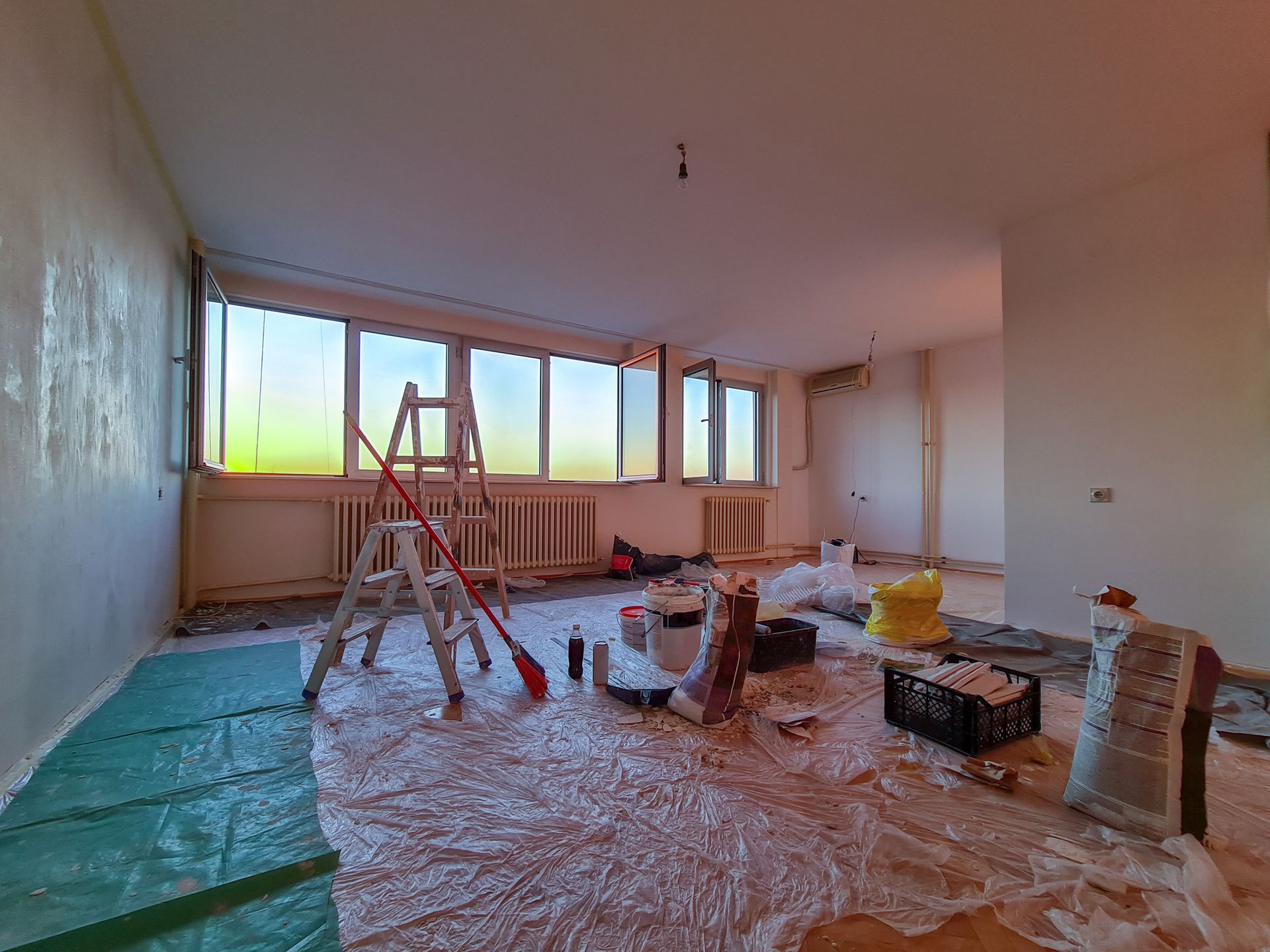 A room is being painted with a ladder and tools on the floor.