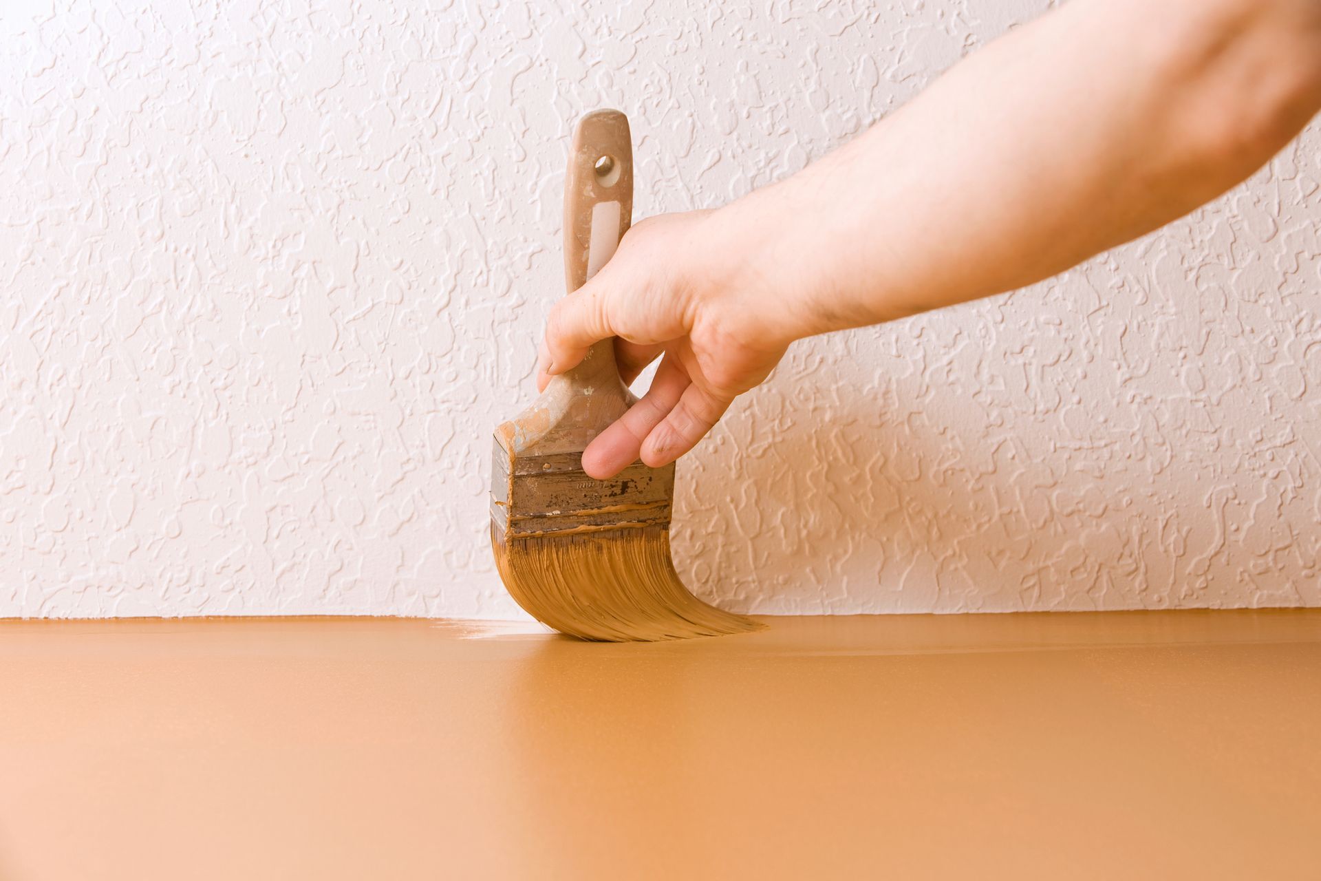 A person is painting a wall with a brush.