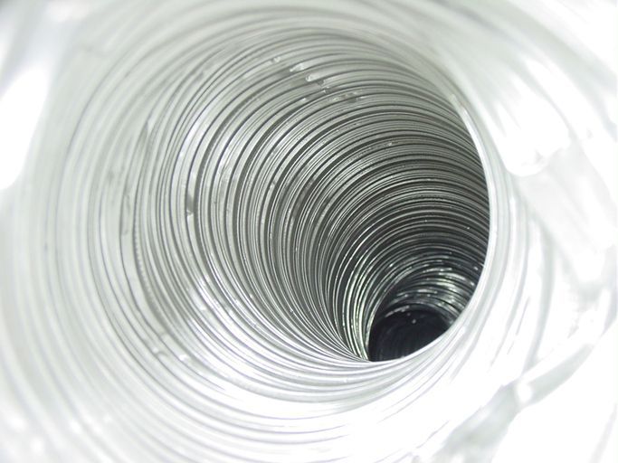 A person is using a vacuum cleaner to clean a duct.