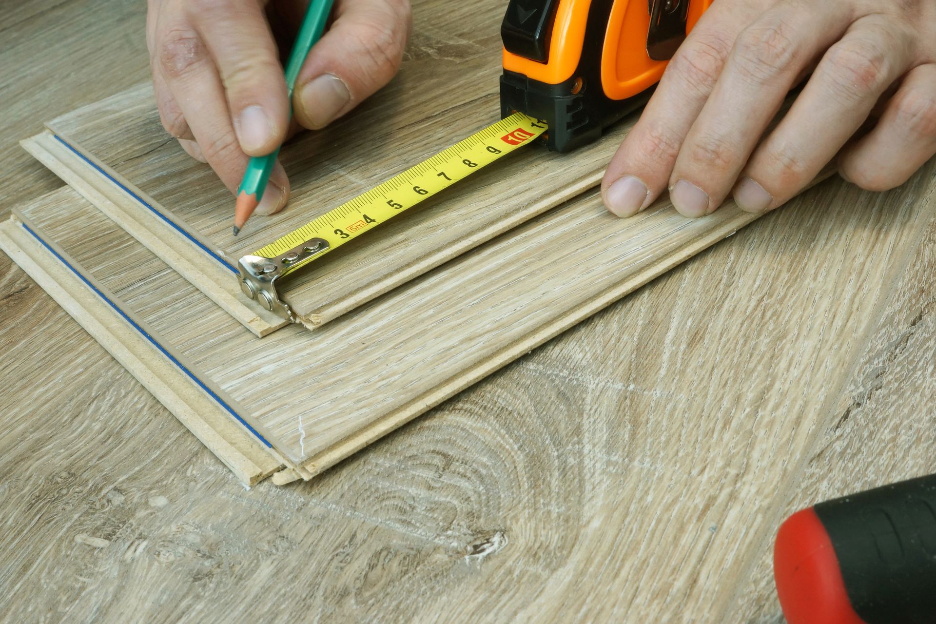 A person is measuring a piece of wood with a tape measure.