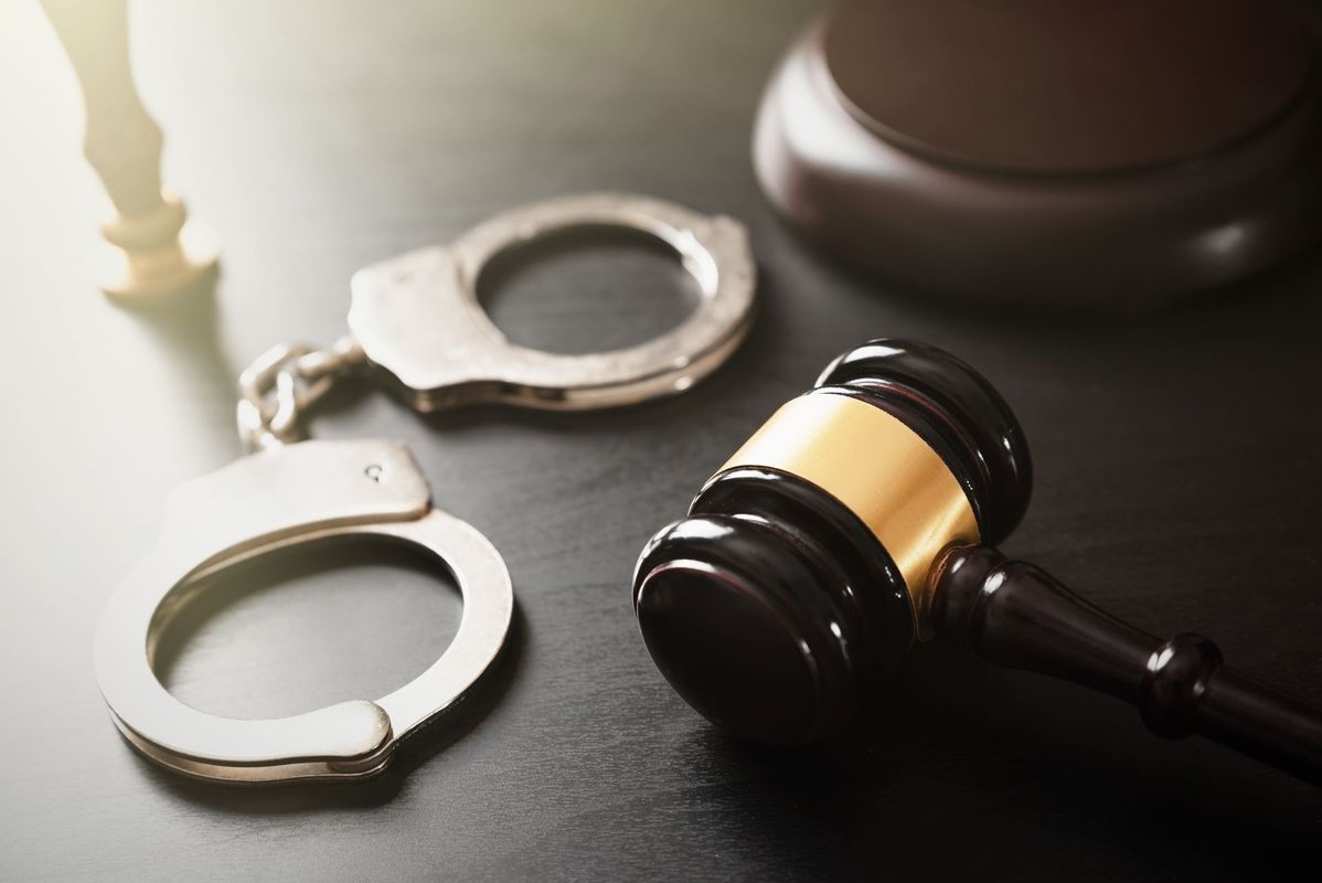 A pair of handcuffs and a judge 's gavel on a table.