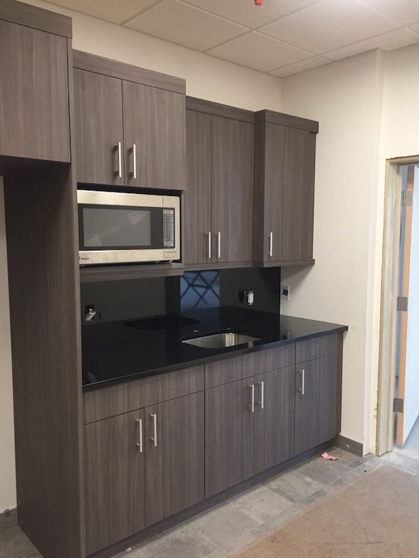 A kitchen with gray cabinets and black counter tops