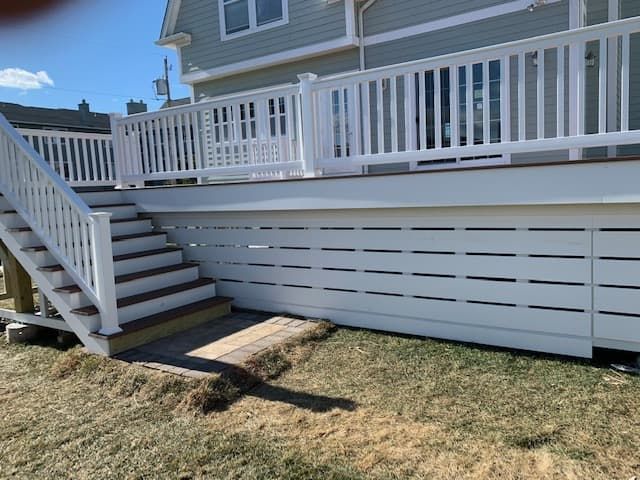 A white deck with stairs leading up to it and a white railing.