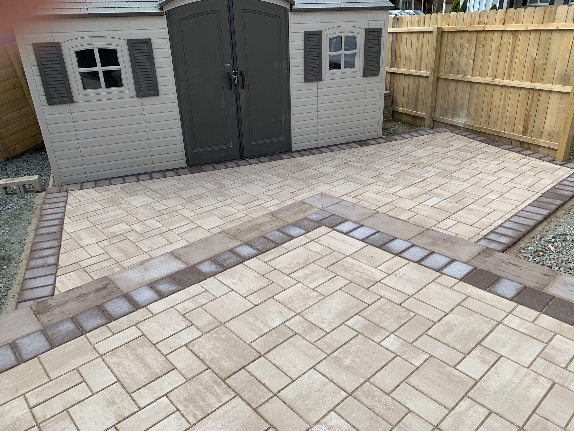 A patio with a shed and a wooden fence in the background.