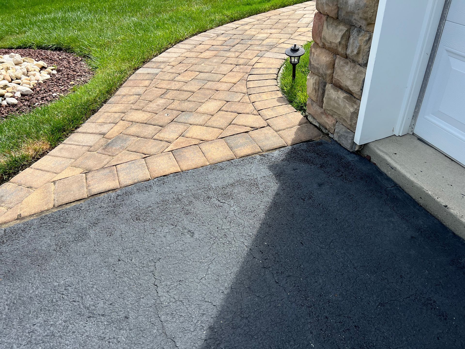 There is a brick walkway leading to a garage door.