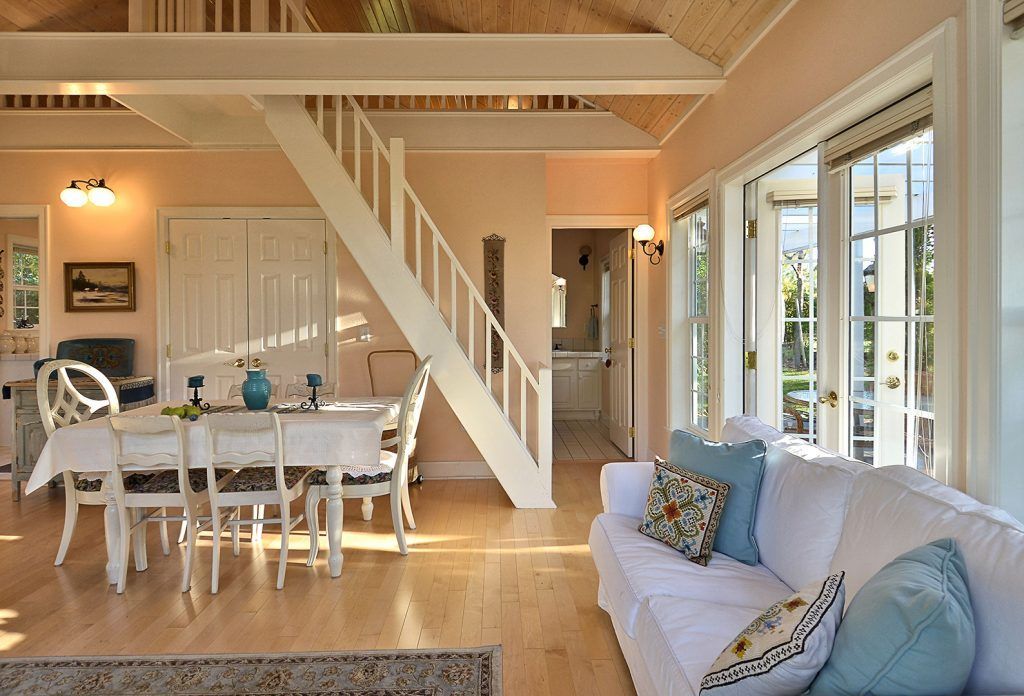 A living room with a couch a table and chairs and a staircase