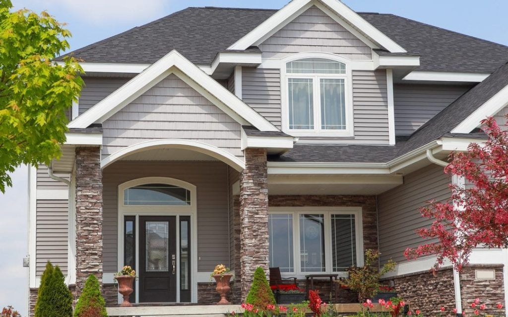 A large house with a large porch and a gray roof.