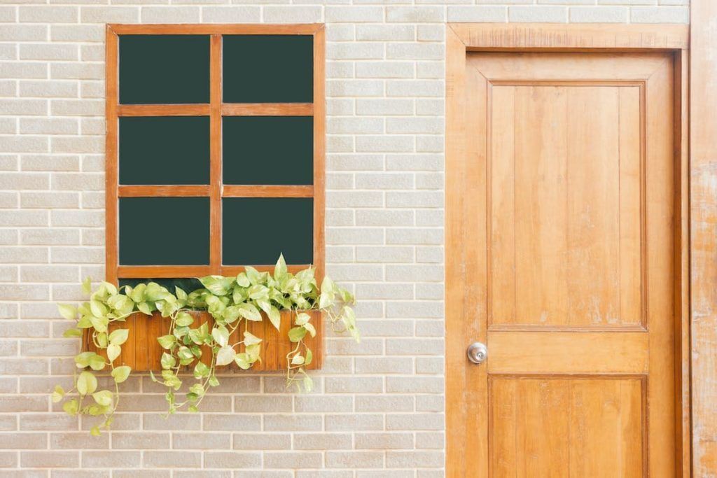 A brick wall with a window and a wooden door.