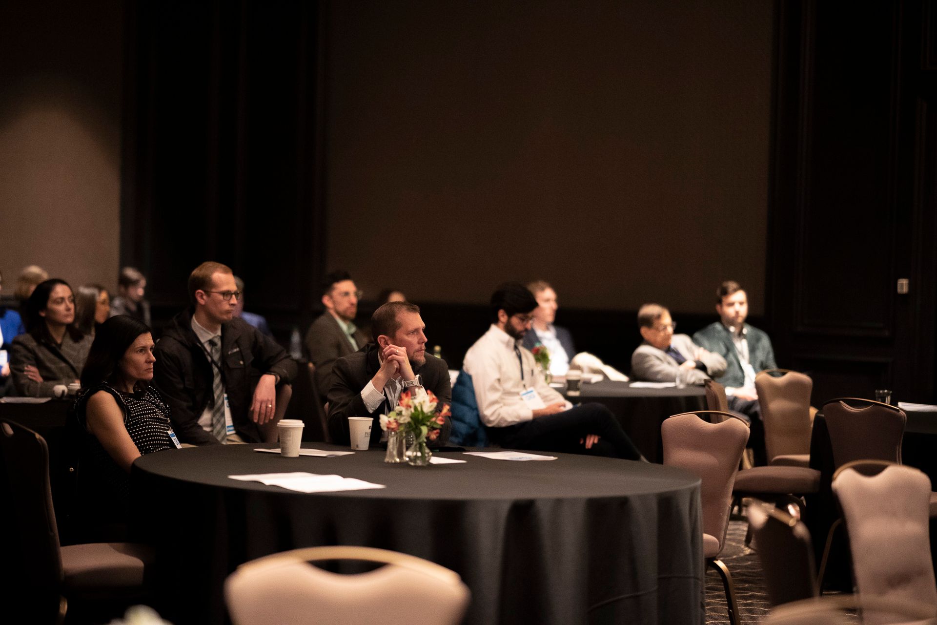 A group of people are sitting at tables in a conference room.