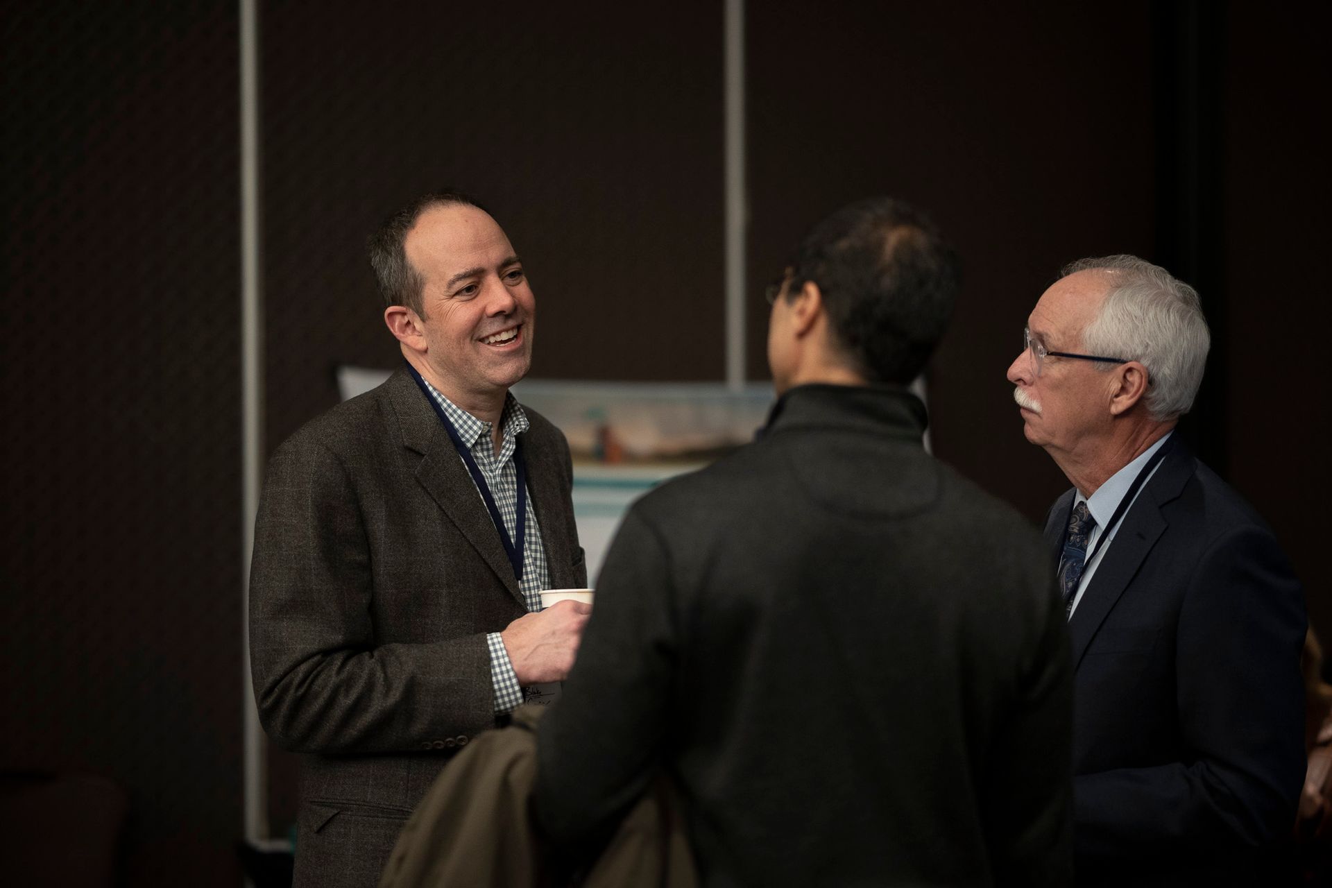 Three men are talking to each other in a dark room.
