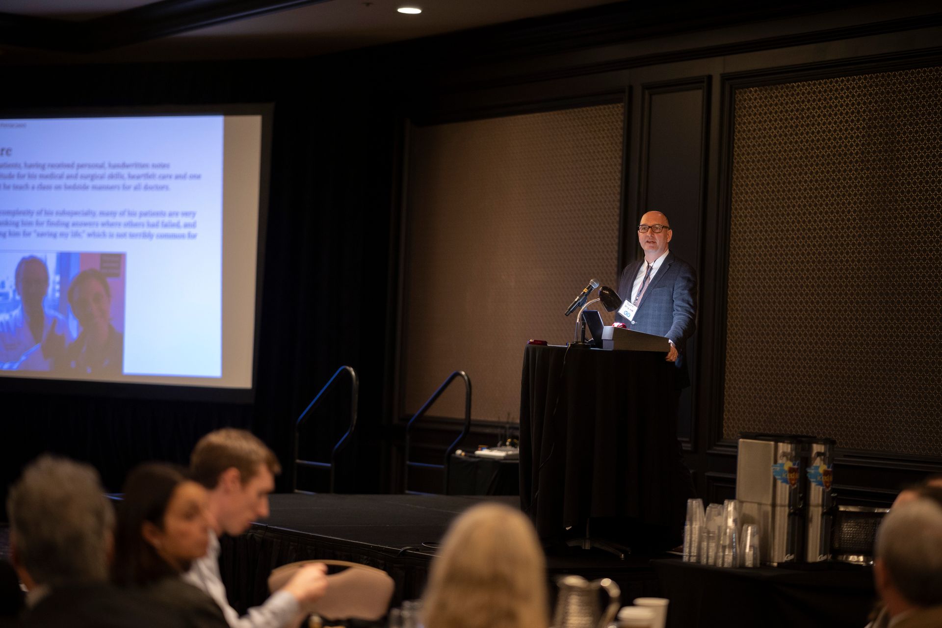 A man is standing at a podium giving a presentation to a group of people.