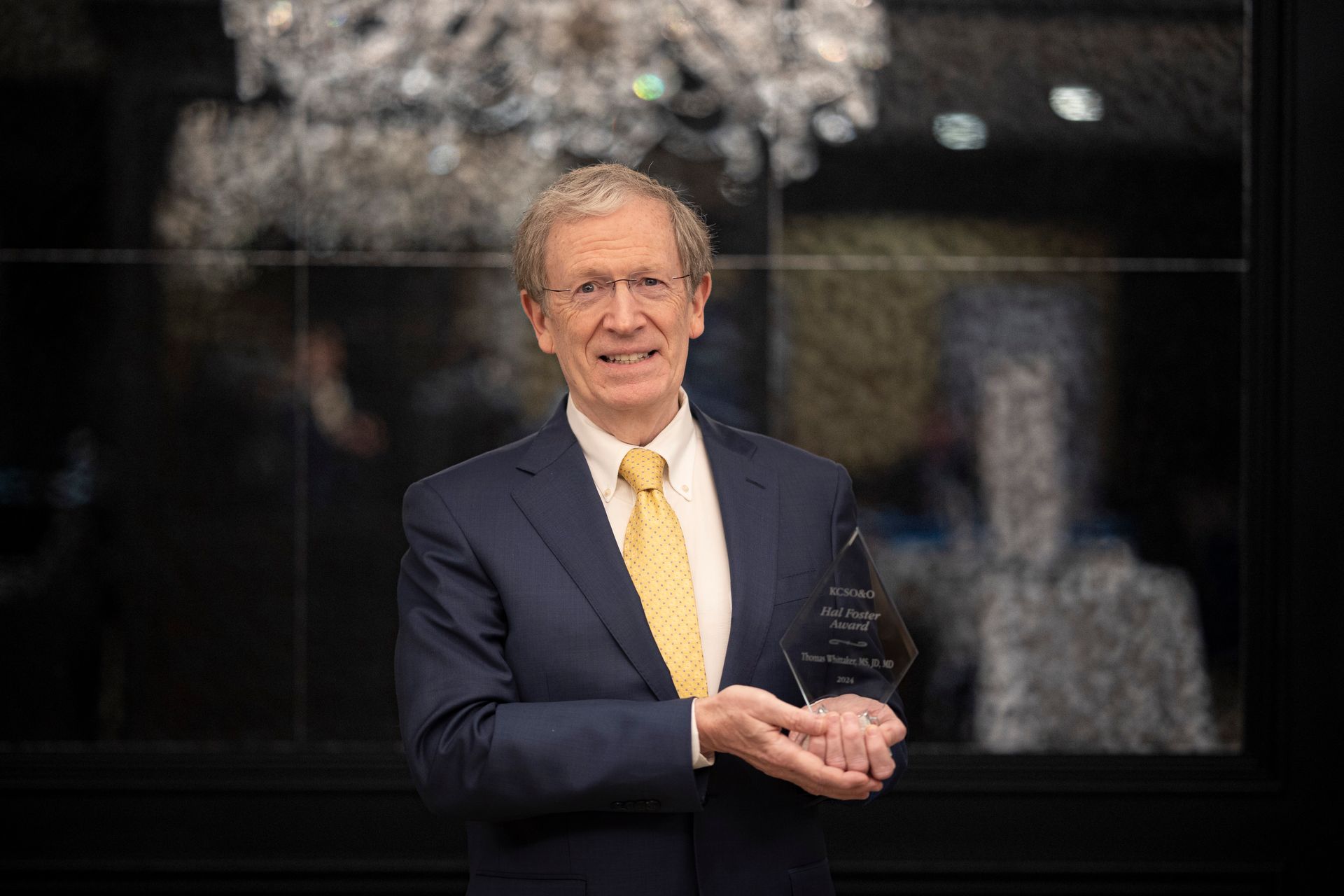 A man in a suit and tie is holding a trophy.