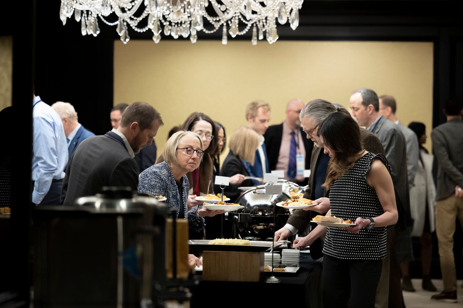 A group of people are standing around a table eating food.