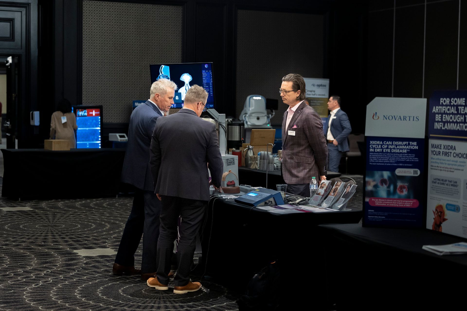 A group of men are standing around a table at a conference.