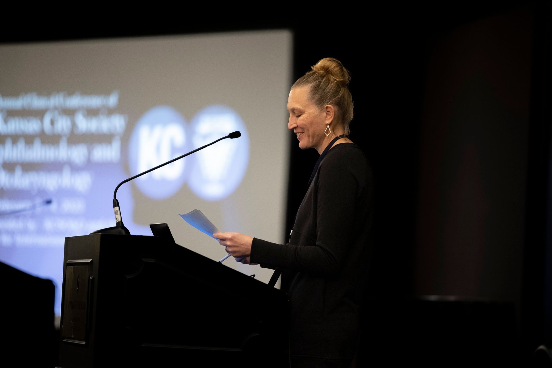 A woman is standing at a podium speaking into a microphone.