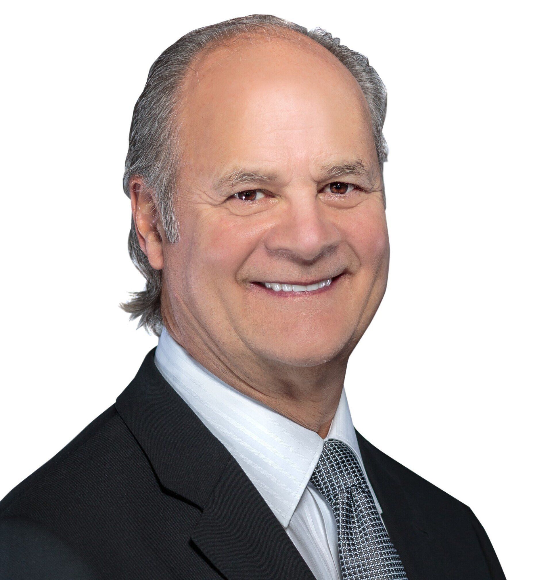 A man in a suit and tie is smiling for the camera