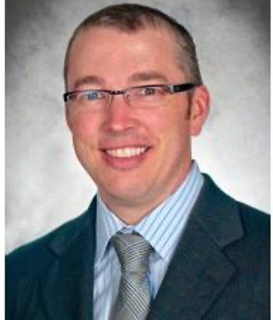 A man in a suit and tie is smiling for the camera.