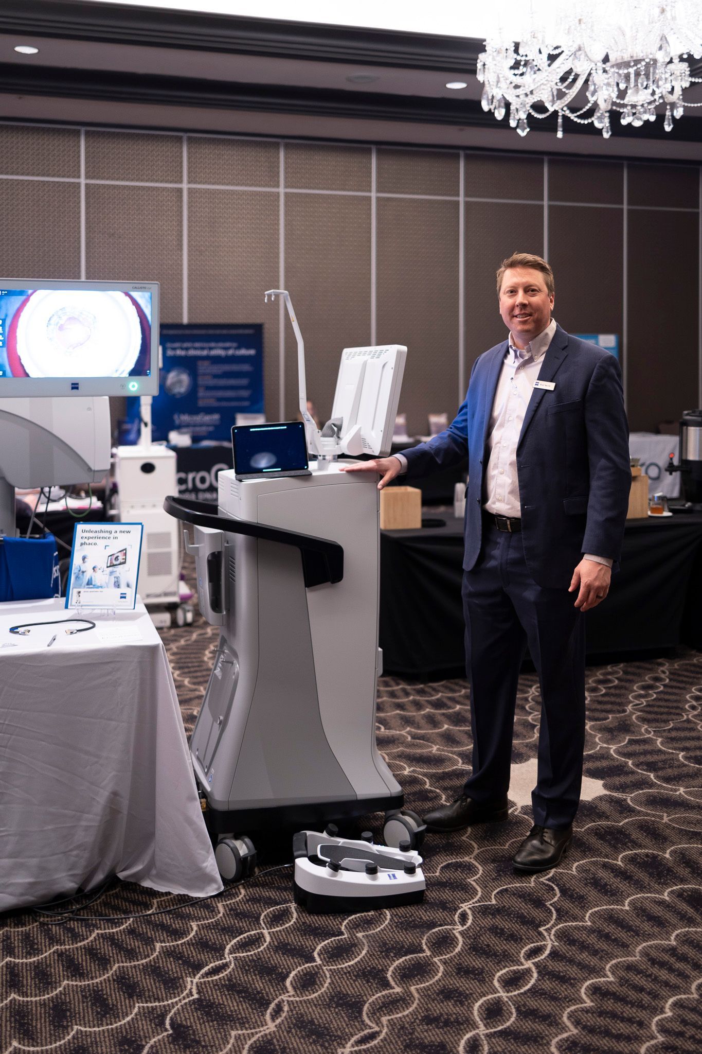 A man in a suit is standing in front of a machine in a room.