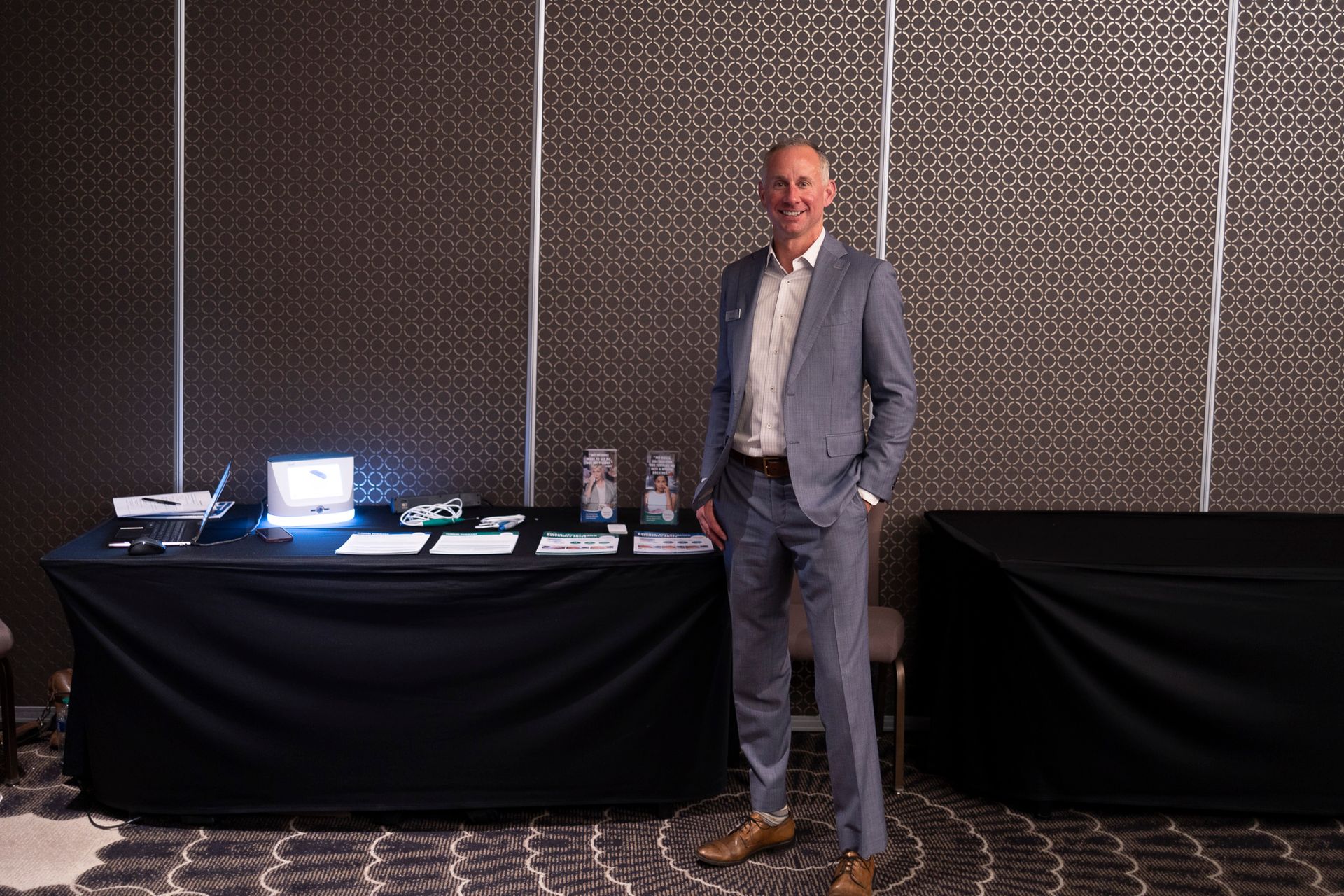 A man in a suit is standing in front of a table.