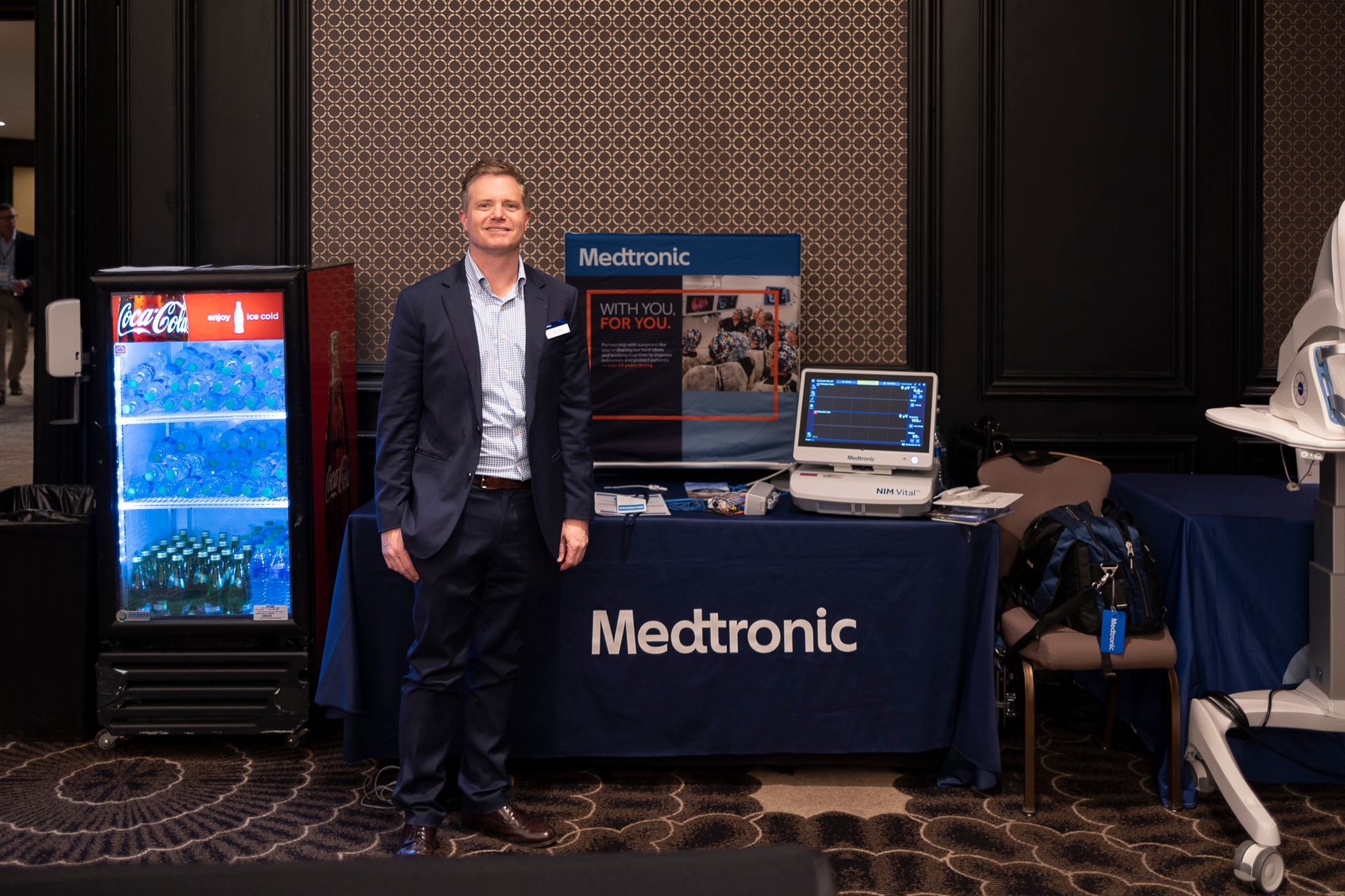 A man in a suit is standing in front of a medtronic table.
