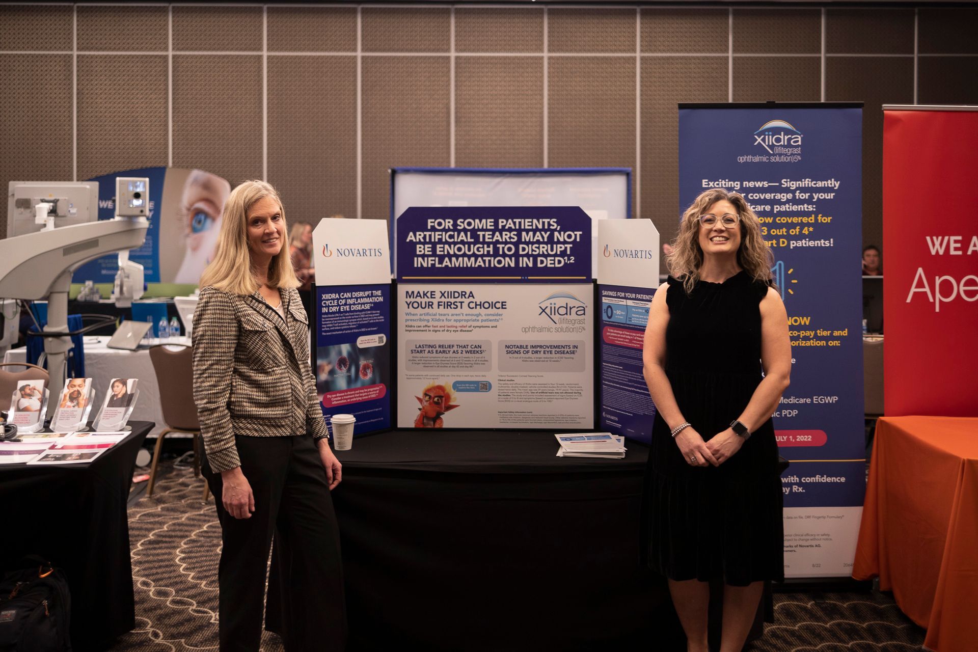 Two women are standing in front of a table at a conference.