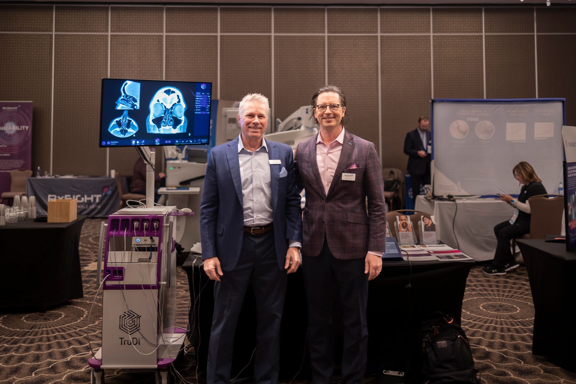 Two men in suits are posing for a picture in front of a machine.