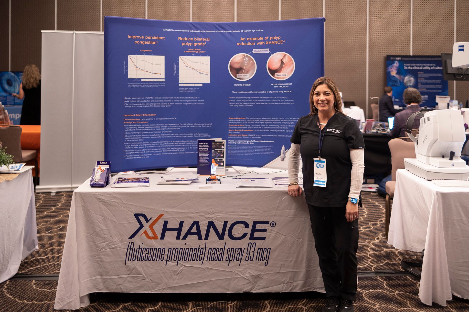 A woman is standing in front of a table that says xchance