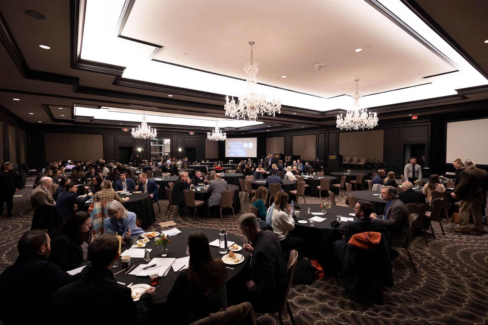 A large room filled with people sitting at tables.